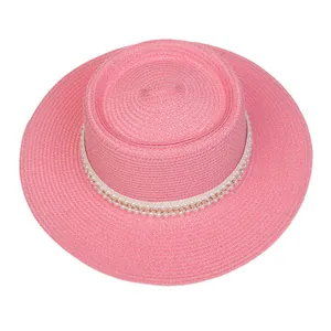 Detailansicht eines rosa Strohhutes mit eleganter Perlen- und Goldkettenverzierung