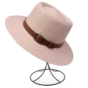 Close-up of pink straw sun hat with brown leather belt detail and metallic buckle