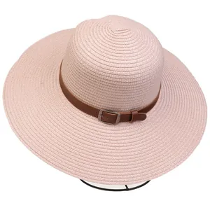 Detailed texture of the wide brim straw hat with brown faux leather belt and metal buckle