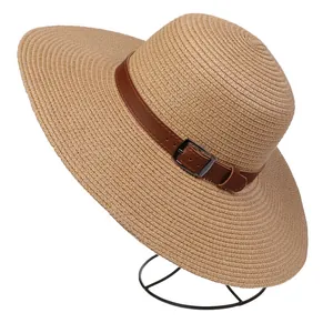 Detail of hand-woven straw hat featuring a brown leather strap and silver metal buckle