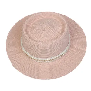 Nahaufnahme des rosa Strohhuts mit eleganter Perlen- und Goldketten-Verzierung