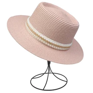 Detailansicht eines rosa Strohhutes mit eleganter Perlen- und Goldkettenverzierung