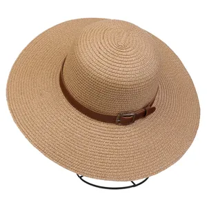 Detail of the woven texture and faux leather belt buckle on a wide brim straw sun hat