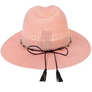 Close-up of pink woven straw hat with elegant black cord and tassel bow detail