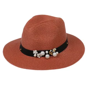 Détail d'un chapeau Panama en paille avec bandeau floral en perles et texture rouge brique