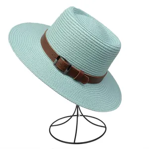 Detail of mint green woven straw hat with brown leather buckle strap decoration