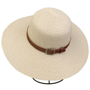 Detail of wide brim straw hat with beige woven texture and brown leather belt buckle