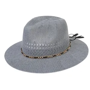 Detailed close-up of grey woven sun hat featuring gold chain and black tassel accents