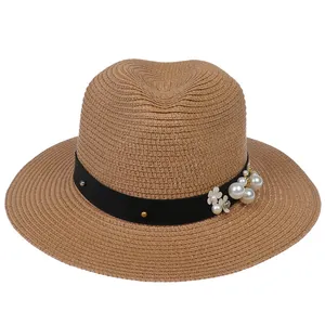 Détail d'un chapeau de paille Panama avec ruban noir, perles blanches et fleurs