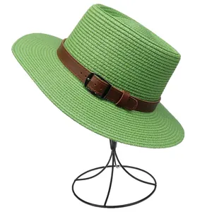 Detailed close-up of grass green straw fedora hat featuring a brown leather belt buckle