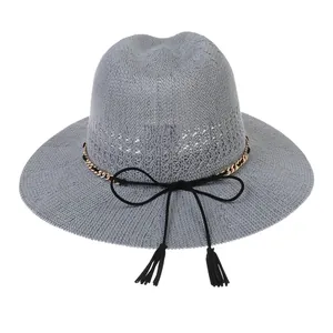 Detail of grey woven sun hat with golden chain and black tassel bow decoration