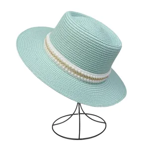 Detail eines minzgrünen Strohhuts mit elegantem Perlen- und Goldketten-Accessoire