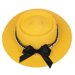 Detail of yellow straw boater hat with black lace, pearls and large satin bow decoration
