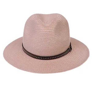 Detail of pink wide brim straw hat featuring a brown leather strap with metal rivets