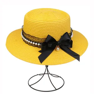Detail of yellow boater hat with black lace, white pearls and a satin bow decoration