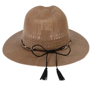 Detail of a brown straw fedora with gold metal chain and black tassel bow tie