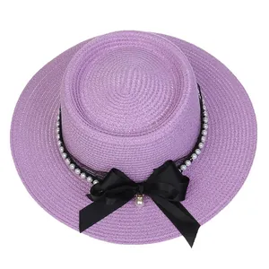 Close-up of purple boater straw hat featuring elegant pearl trim and black ribbon bow detail