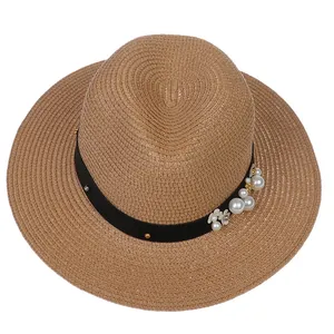 Détail d'un chapeau panama en paille marron avec ruban noir orné de perles et fleurs