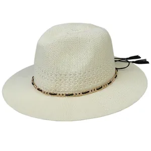 Detailed close-up of woven straw hat with golden chain and black tassel accents