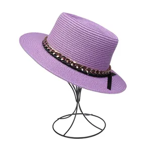 Detailstruktur eines violetten Strohhuts mit schwarzem Band und goldener Kettendekoration