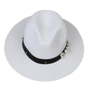 Détail du chapeau Panama blanc avec ruban noir, perles et clous métalliques