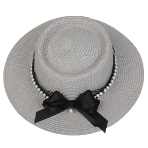 Detailed view of woven straw boater hat with black ribbon, lace, and white pearl trim