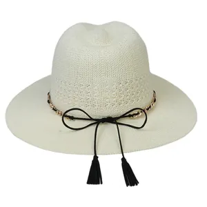 Detailed texture of beige woven straw hat with golden chain and black tassel bow decoration