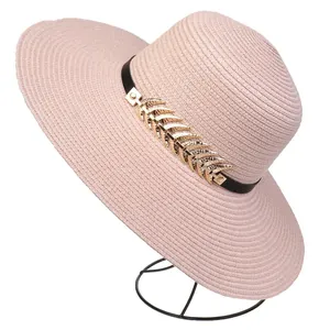 Detailed texture of a wide-brim straw sun hat with black leather band and gold leaf accent