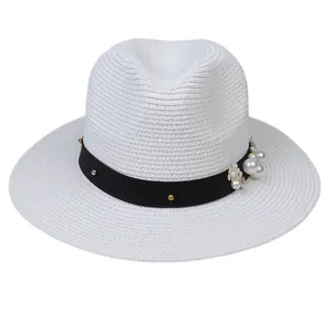 Détail d'un chapeau Panama avec ruban noir, clous, perles et accents floraux