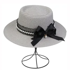 Detail of dark grey boater hat with black lace, pearls, and large satin bow