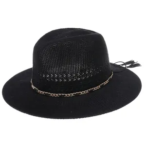 Detail of black woven straw hat featuring a gold metal chain and stylish tassel accents