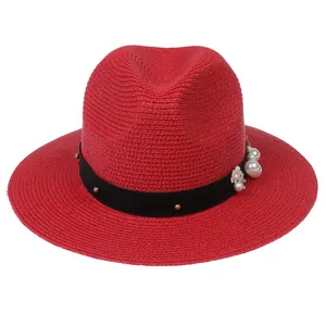 Détail du chapeau de paille rouge avec bande à rivets noirs et accessoire fleurie