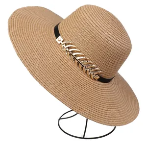 Detailed macro view of woven straw sun hat with leather band and golden leaf ornament