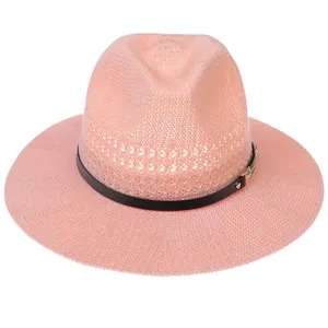 Close-up of pink woven straw hat featuring black leather band and gold metal buckle