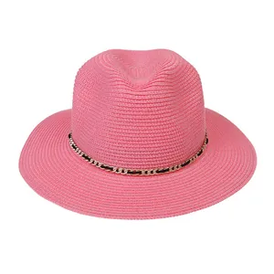 Close-up of pink woven straw fedora hat featuring a stylish gold chain band detail