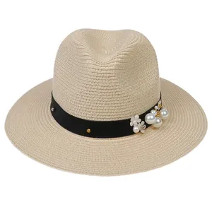 Détail des perles et fleurs sur le ruban noir d'un chapeau de paille Panama beige chic