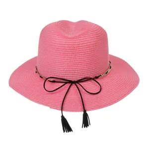 Detail of pink straw sun hat texture with gold chain bow and black tassel trim