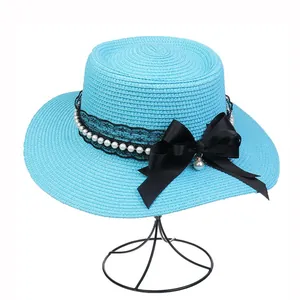 Detail of bright blue boater hat featuring black lace, pearls, and a large satin bow