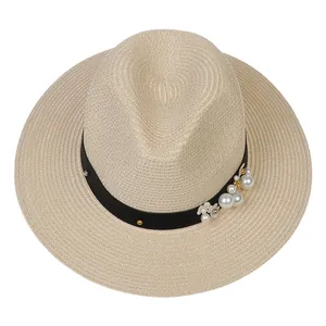Détail du chapeau de paille Panama avec perles et clous dorés sur ruban noir