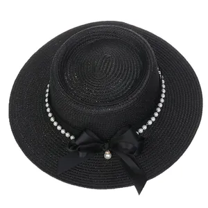 Detail of elegant black straw hat featuring premium pearl trim and a satin bow accessory