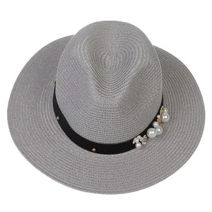 Détail d'un chapeau Panama gris clair avec ruban noir orné de perles et de fleurs blanches