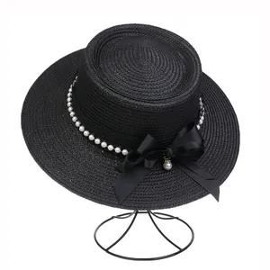Close-up of black boater straw hat with elegant pearl beads and satin bow decoration