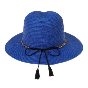 Close-up of blue straw panama hat with gold chain detail and decorative black tassels