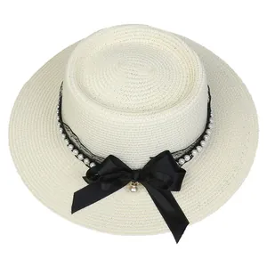 Detail of cream straw hat featuring black lace, white pearls, and a large satin bow accent