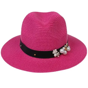 Détail d'un chapeau panama rose avec ruban noir orné de perles et de petites fleurs blanches