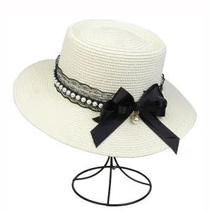 Close-up of elegant off-white straw hat with black lace, pearls and satin bow detail