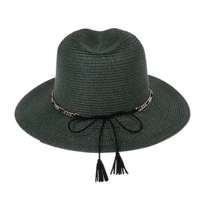 Detailed close-up of dark green woven straw hat with elegant gold chain and tassel detail