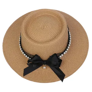 Detail view of straw hat featuring black lace ribbon, satin bow and pearl accents