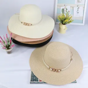 Close-up of woven straw sun hats with white twisted rope and gold chain buckle detail