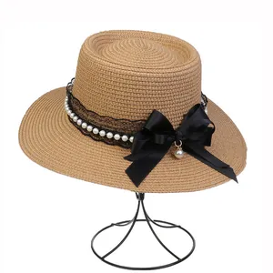 Detail of elegant straw hat with black lace, large satin bow and pearl decorations